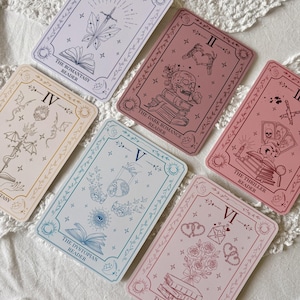 May include: Six rectangular cards with tarot-style illustrations and text. Each card features a Roman numeral and a specific genre title: The Romantasy Reader, The Dark Romance Reader, The Thriller Reader, The Dystopian Reader, and The Romance Reader.