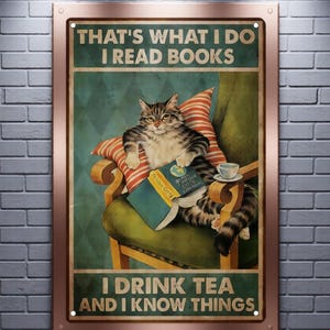 May include: A rectangular metal sign featuring a tabby cat sitting in a green armchair, reading a book with a cup of tea nearby. The text reads: THAT'S WHAT I DO I READ BOOKS I DRINK TEA AND I KNOW THINGS. The sign has a copper-colored frame.