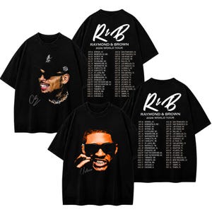 May include: Black short-sleeve t-shirts featuring graphic prints. One design shows a person in a cap and sunglasses with the text "CB". The other design displays "R&B RAYMOND & BROWN 2026 WORLD TOUR" with a list of cities and dates in white text.