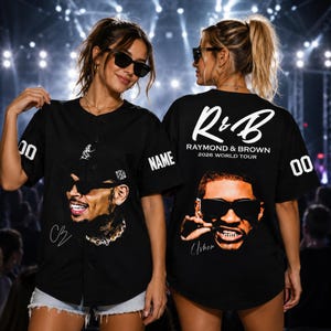Könnte beinhalten: Ein schwarzes Baseballtrikot mit Knopfleiste und einer Grafik einer Person mit Sonnenbrille auf der Vorder- und Rückseite. Auf der Rückseite steht der Text R&B RAYMOND & BROWN 2026 WORLD TOUR. Die Ärmel zeigen die Nummer 00 und das Wort NAME.