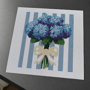 May include: A square needlepoint canvas featuring a cross-stitch design of a blue hydrangea bouquet tied with a cream-colored ribbon. The flowers are set against a background of vertical light blue and white stripes on a white grid mesh.