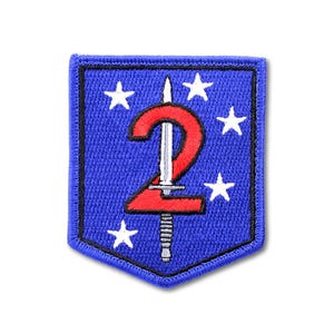 May include: A shield-shaped embroidered patch featuring a blue background with a black border. A large red number two is centered, overlaid by a silver bayonet pointing upward. Five white stars are arranged around the central design elements.