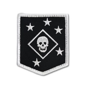 Könnte beinhalten: Ein schildförmiger gestickter Aufnäher mit schwarzem Hintergrund und weißem Rand. Das Design zeigt eine zentrale weiße Raute mit einem detaillierten weißen Totenkopf, umgeben von fünf weißen Sternen, die kreisförmig um die Raute angeordnet sind.