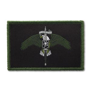 May include: A rectangular black embroidered patch with an olive green stitched border. The design features a central eagle with outstretched wings clutching a vertical sword. A banner above the sword reads SPIRITUS INVICTUS, and a shield with a skull emblem sits on the blade.
