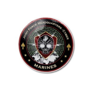 May include: A circular sticker featuring the text JOINT FORCE HEADQUARTERS - CYBER MARINES. The design includes a central shield with a skull motif, circuit board patterns, binary code, a world map, and gold spearhead and star accents on a black background.