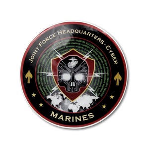 May include: A circular sticker featuring the text JOINT FORCE HEADQUARTERS - CYBER MARINES. The design includes a central shield with a skull and circuit board pattern, a globe silhouette, binary code, lightning bolts, and gold spade icons.