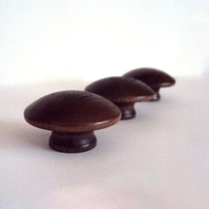 May include: Four brown wooden mushroom-shaped cabinet knobs.