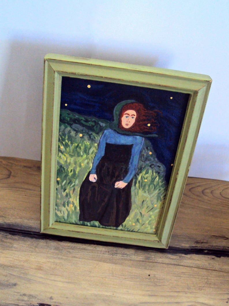 Op de afbeelding: Een ingelijst schilderij van een vrouw met rood haar die een blauwe en zwarte jurk draagt, staand in een veld met groen gras onder een donkerblauwe lucht met gele sterren.