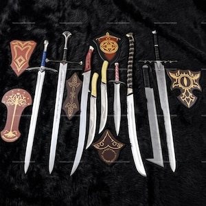 May include: A collection of metal swords and daggers with various blade shapes and hilt designs, accompanied by several decorative wooden wall plaques featuring gold-colored patterns, arranged together on a dark, textured surface.