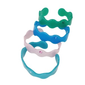 May include: Four colorful, wavy-edged bracelets in shades of green, blue, and pink. Each bracelet has a small, sparkling gem. The bracelets are stacked on top of each other, creating a playful and eye-catching display.