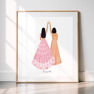 May include: A framed art print featuring two figures in formal dresses, raising champagne glasses in a toast. One figure wears a pink dress, the other an orange dress. The phrase "love you lots" is written at the bottom.