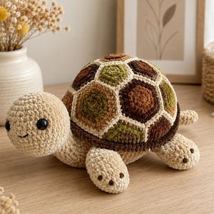 May include: A crochet turtle plush toy featuring a cream-colored head and limbs with black plastic eyes. The shell is constructed from hexagonal patches in shades of olive green, dark brown, and tan, outlined with a cream-colored yarn border.