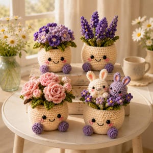 Può includere: Quattro vasi all'uncinetto color crema con facce sorridenti e piedini viola, ognuno contenente diversi arrangiamenti in filato fatti a mano: fiori viola, steli di lavanda, rose rosa e due piccoli coniglietti bianchi e viola con fiori.