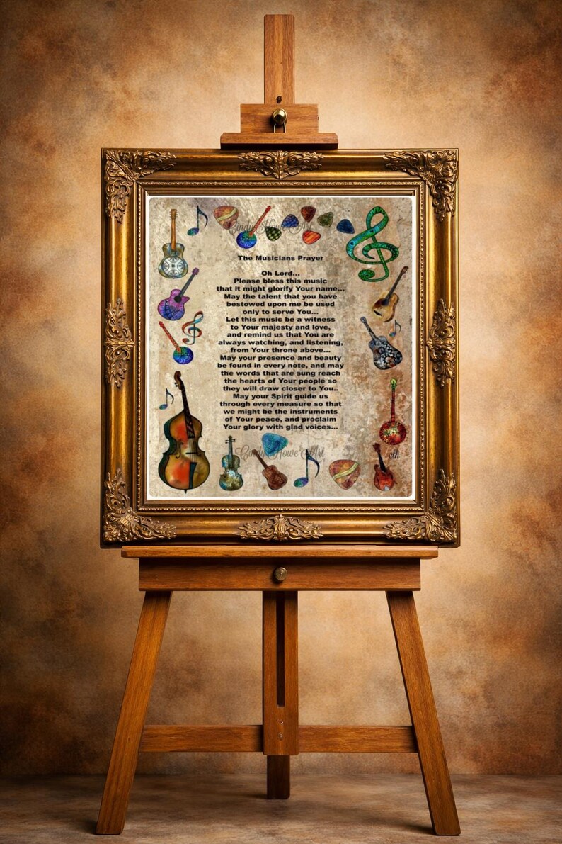 May include: A framed print on an easel features "The Musicians Prayer" with musical instrument illustrations. The gold frame surrounds the text and colorful drawings of guitars, violins, and musical notes. The easel is made of wood.