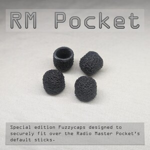 Peut inclure: Quatre petits capuchons cylindriques noirs texturés avec l'inscription RM Pocket. Le texte ci-dessous indique : Special edition Fuzzycaps designed to securely fit over the Radio Master Pocket's default sticks. Surface poreuse et rugueuse.