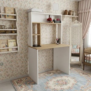 May include: A white and light wood desk with an integrated hutch featuring open shelving. The desk has a flat work surface, vertical side partitions, and a top shelf. The structure is composed of white side panels and a light wood desktop.