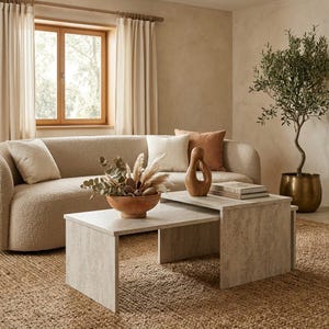May include: A set of two nested coffee tables with a light gray stone-like finish. The tables feature a rectangular design with flat tops and solid side panels, arranged in a tiered configuration on a textured woven rug in a living room.