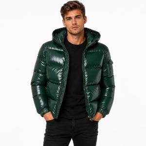 Könnte beinhalten: Eine glänzende dunkelgrüne Daunenjacke mit Kapuze, horizontalen Steppnähten, einem Frontreißverschluss und einer kleinen Utility-Tasche am linken Ärmel. Die Jacke wird über einem schlichten schwarzen T-Shirt und einer dunklen Jeans getragen.