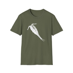 Pode incluir: Uma t-shirt de manga curta verde-azeitona com uma impressão gráfica branca de um copépode, um pequeno crustáceo aquático, centrada no peito. O design mostra o corpo segmentado detalhado e as antenas do organismo num estilo de esboço.