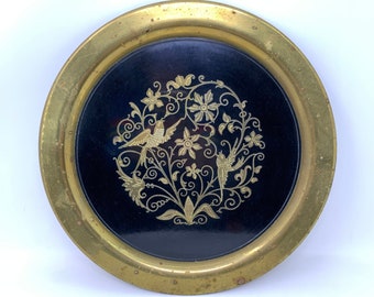May include: A round brass tray with a black center featuring a gold floral design with two birds.