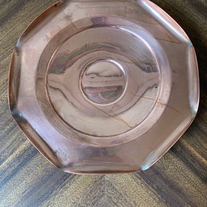 May include: A round, octagonal copper serving tray with a raised center. The tray has a shiny, polished finish and is perfect for serving snacks or appetizers.