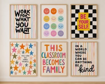 May include: Six framed wall art prints featuring colourful designs. One has vertical stripes with the text 'WORK FOR WHAT YOU WANT', one has a grid of multicoloured smiley faces, one has a black and white checkerboard with 'BE YOUR SELF.', one has multicoloured stars with 'YOU CAN DO HARD THINGS', one has 'THIS CLASSROOM BECOMES FAMILY' in rainbow letters, and one has vertical stripes with 'IN A WORLD WHERE YOU CAN BE ANYTHING BE kind'.