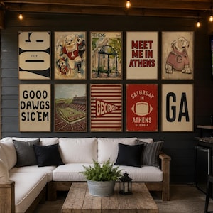 May include: A gallery wall featuring ten framed posters with University of Georgia themes, including illustrations of a bulldog, a stadium, and text such as '706', 'Meet Me In Athens', 'Goood Dawgs Sic'em', 'Saturday In Athens', and 'Go Dawgs' neon sign.