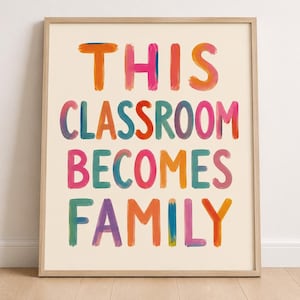 Può includere: Una stampa artistica da parete incorniciata con il testo THIS CLASSROOM BECOMES FAMILY in lettere multicolori in stile pennellata. Le lettere sono realizzate in tonalità arancione, rosa, blu, rosso e viola su uno sfondo color crema chiaro.