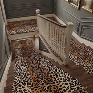 May include: A staircase featuring a leopard print runner carpet secured with a gold metal rod. The runner covers the wooden steps and landing, contrasting with the dark gray paneled walls, white wooden balustrade, and framed wall art.