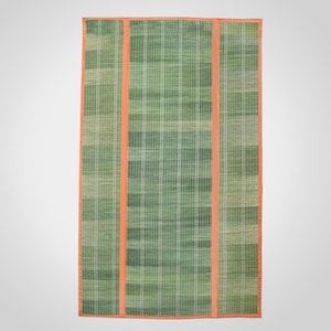 Puede incluir: Una alfombra tejida rectangular con un patrón de cuadros en verde y verde claro. La alfombra está dividida en tres secciones verticales por dos tiras de tela naranja sólida, con un borde de tela naranja a juego en todo el contorno.