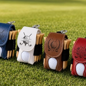 May include: Four small golf ball pouches in navy blue, white, brown, and red leather, each featuring a metal clip, a golf ball, and wooden tees. The flaps are engraved with golf-themed graphics and the names Anderson, Ethan, CS, and William.