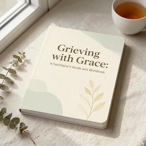 May include: A softcover book titled Grieving with Grace: A Facilitator's Guide and Workbook. The cover is cream-colored with sage green abstract shapes, a gold-toned line drawing of a leafy branch, and dark brown text centered on the front.