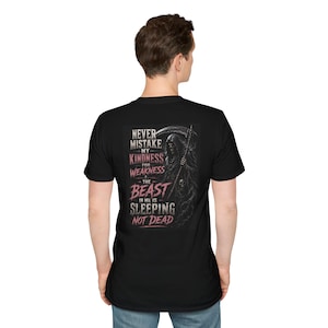May include: A black t-shirt featuring a graphic on the back with a grim reaper illustration and the text: NEVER MISTAKE MY KINDNESS FOR WEAKNESS THE BEAST IN ME IS SLEEPING NOT DEAD. The design uses white and pinkish-red lettering on a dark background.