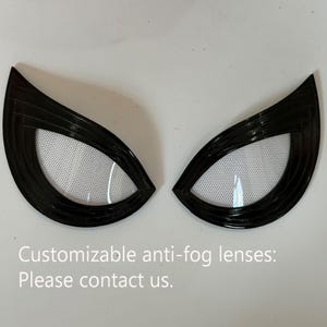 Könnte beinhalten: Ein Paar schwarze, winklige, augenförmige Linsen mit einem weißen Netzgitter im Inneren. Die Linsen verfügen über ein geschichtetes, geriffeltes Rahmendesign. Der Text auf dem Bild lautet: Customizable anti-fog lenses: Please contact us.