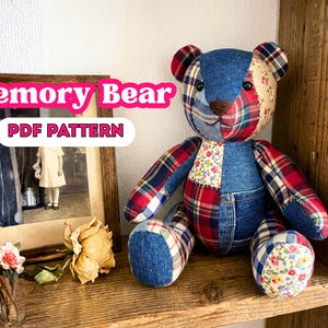 May include: A stuffed bear made from patchwork fabric, including blue denim, red and blue plaid, and floral print cotton. The bear has dark button eyes and a brown stitched nose. Text in the image reads Memory Bear PDF PATTERN.