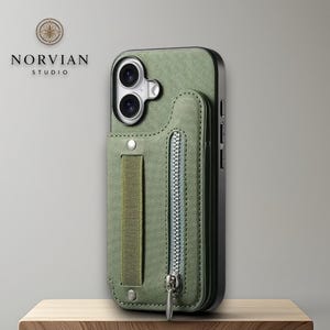 May include: An olive green textured phone case featuring a vertical elastic strap and a small zippered pocket on the back. The case includes a cutout for a dual-lens camera system. The Norvian Studio logo is visible in the upper left corner.