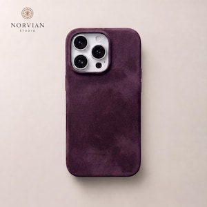 Op de afbeelding: Een donkerpaarse telefoonhoes met suèdetextuur voor een iPhone met een drievoudig camerasysteem. De hoes heeft een uitsparing voor de cameramodule en is voorzien van de tekst NORVIAN STUDIO in de linkerbovenhoek van het beeld.