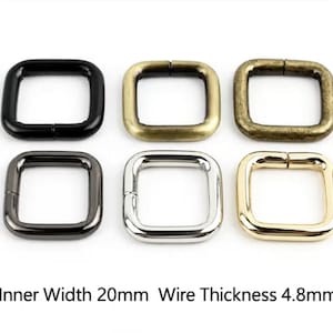 Puede incluir: Seis anillos metálicos cuadrados dispuestos en dos filas, con acabados en negro, latón antiguo, bronce, bronce plomizo, plata y oro. Cada anillo tiene un ancho interior de 20mm y un grosor de alambre de 4,8mm, según indica el texto inferior.