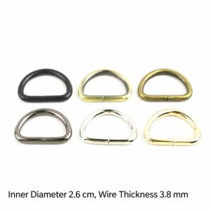 Puede incluir: Seis anillas en D con diversos acabados metálicos, incluyendo negro mate, latón antiguo, bronce, plata y oro. Cada anilla tiene un diámetro interior de 2,6 cm y un grosor de alambre de 3,8 mm. Estos herrajes están dispuestos en dos filas.