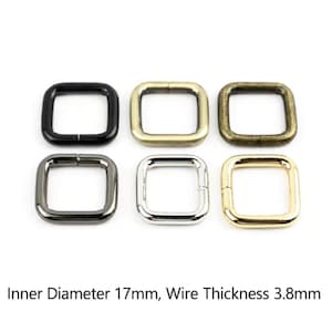 Op de afbeelding: Zes vierkante metalen ringen in verschillende afwerkingen, waaronder zwart, messing, antiek brons, gunmetal, zilver en goud. Elke ring heeft een binnendiameter van 17 mm en een draaddikte van 3,8 mm, zoals aangegeven onder de objecten.