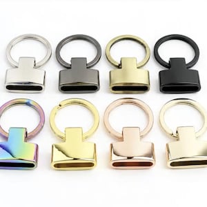Può includere: Una collezione di otto chiusure in metallo per portachiavi disposte su due file. Il set include varie finiture come argento, canna di fucile, ottone antico, nero opaco, arcobaleno iridescente, oro brillante, oro rosa e oro chiaro lucido.