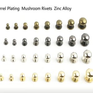 以下が含まれることがあります： 亜鉛合金製のマッシュルームリベットのコレクション。ブロンズ、ガンメタル、シルバー、ゴールドの各色で4つの水平な列に並べられています。各列にはサイズが大きくなる8つのリベットが含まれています。テキストには「Barrel Plating Mushroom Rivets Zinc Alloy」と書かれています。