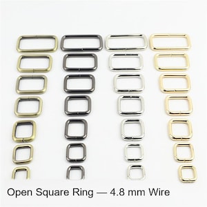 Puede incluir: Una colección de anillos cuadrados abiertos de metal dispuestos en cuatro columnas verticales por color: latón antiguo, bronce, plata y oro. Cada columna presenta anillos de varios tamaños, con el texto Open Square Ring — 4.8 mm Wire.