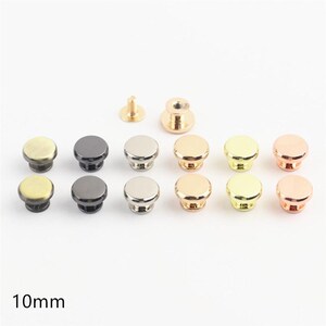 Peut inclure: Un ensemble de boutons métalliques de 10 mm dans diverses finitions, notamment laiton antique, bronze, argent, or et or rose. Le lot comprend des capuchons de boutons circulaires et des fixations filetées assorties, présentés par paires.