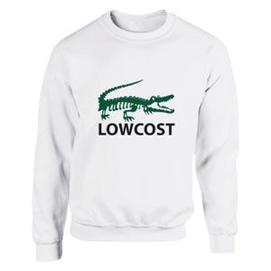 Puede incluir: Una sudadera blanca de manga larga con un gráfico verde de un esqueleto de cocodrilo en el pecho. Debajo del esqueleto de cocodrilo verde, la palabra LOWCOST está impresa en letras mayúsculas negras en negrita. Tiene cuello redondo.