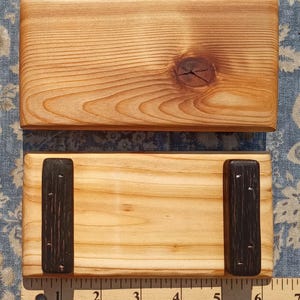 May include: Two rectangular light-colored wooden blocks with visible grain patterns. The top block features a dark wood knot. The bottom block has two dark, textured wooden feet attached. A Westcott ruler shows the length is approximately 6.5 inches.