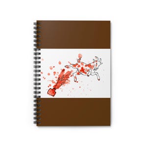 Könnte beinhalten: Ein spiralgebundenes Notizbuch mit einem einfarbig braunen Einband und einem zentralen weißen rechteckigen Feld. Das Feld zeigt eine Aquarellillustration einer weißen Ziege mit orangefarbenen Flecken, die von einem spritzenden Tintenfass wegspringt.