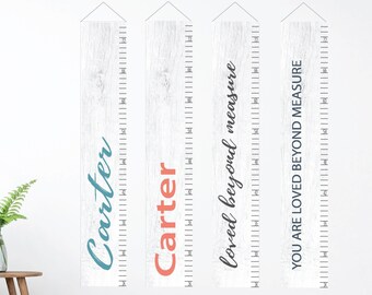 May include: Three white wooden growth charts with black ruler markings. The first chart says "Carter" in teal blue lettering. The second chart says "Carter" in coral lettering. The third chart says "loved beyond measure" in black lettering.