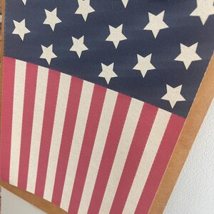 May include: A clipboard featuring a patriotic design. The top portion displays a navy blue background with white stars, while the bottom half showcases red and white stripes. The metal clip is visible at the top.