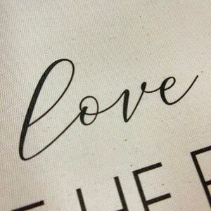 May include: Close-up of a white canvas sign with black text that reads "love together".